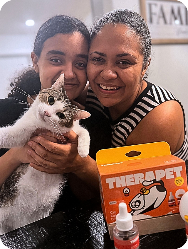 Pet parent holding a calm cat beside TheraPet products